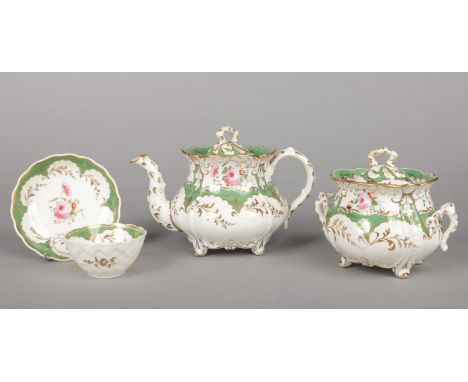 A Rockingham teapot, sucrier and teacup and saucer with rustic handles and basket weave moulding to the cup. Painted with gre