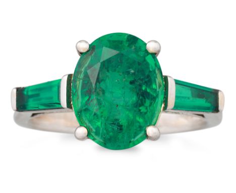 AN EMERALD RING, the oval emerald to emerald shoulders, mounted in 18ct white gold. Estimated: weight of centre emerald: 3.56