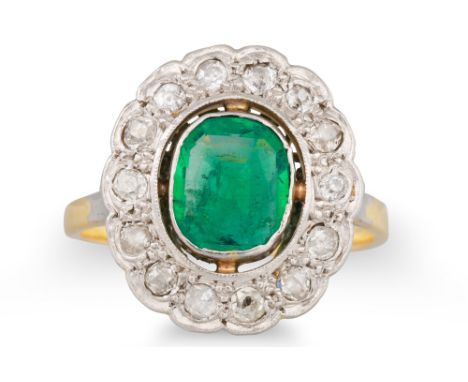 AN EDWARDIAN EMERALD AND DIAMOND CLUSTER RING, the oval emerald to old cut diamond surround, mounted in yellow and white gold