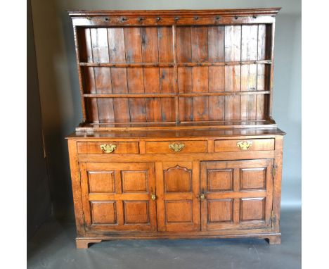 A George III Oak Dresser, the boarded shelf back above three frieze drawers and a central panel flanked by panel doors all ra