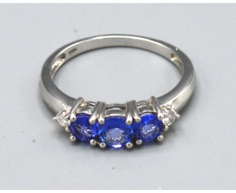 An 18ct. White Gold Tanzanite and Diamond Ring set with three tanzanite flanked by small diamonds, claw set, ring size N, 3.1