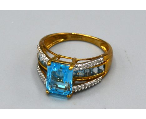 A 9ct. Gold Dress Ring set with a central rectangular blue stone with diamond shoulders, ring size N, 3.3 gms. 