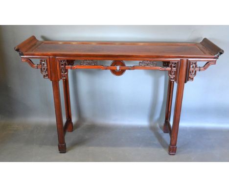 A Chinese Hardwood Altar Table, the shaped top with scroll ends above a carved frieze with central roundel raised upon square