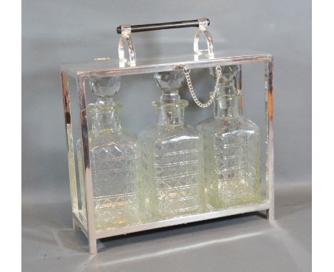 A Silver Plated Tantalus, the hinged top above three cut glass decanter with stoppers 28cm by 10cm and 24.5cm tall 