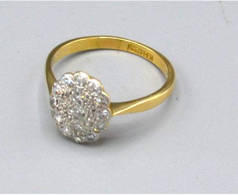 An 18ct. Gold and Platinum Diamond Set Cluster Ring of oval form, ring size M, 2.6 gms. 