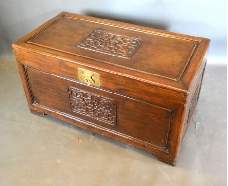 A Chinese Hardwood Trunk, the hinged cover above a carved front with brass lock, 104 cms wide, 53.5 cms deep, 55 cms high 