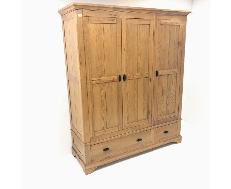 Light oak triple wardrobe, projecting cornice, three doors enclosing hanging rail and shelves above two drawers,  shaped brac