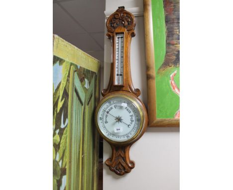 An early 20th century carved oak cased barometer with enamel dial 