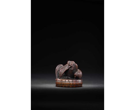A JAPANESE WOOD NETSUKE OF CHICKENSCarved as a cockerel and hen perched on a war drum, the birds realistically depicted; the 