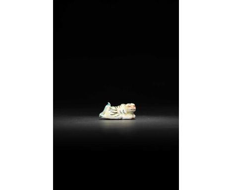 A JAPANESE PORCELAIN NETSUKE OF A TIGER MEIJI ERA, 19TH CENTURY  The feline is depicted crouching with its long tail curling 