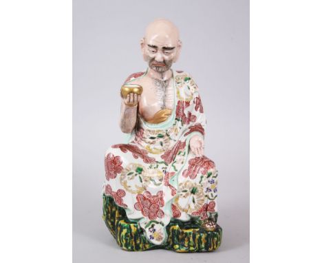 A GOOD JAPANESE KUTANI PORCELAIN MODEL OF AN ARHAT, the arhat with a low expression upon his face, seated upon a rock formed 