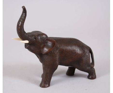 A JAPANESE MEIJI PERIOD BRONZE ELEPHANT OKIMONO, stood in a moving pose with his trunk aloft, modelled with carved ivory tusk