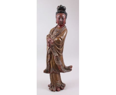 AN EARLY CHINESE CARVED WOOD FIGURE OF GUANYIN, stood with her hands crossed holding a scroll, wearing traditional robes, the