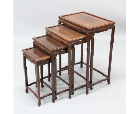 A 19TH CENTURY CHINESE HARDWOOD NEST OF FOUR TABLES, the aprons carved with simplistic scroll carvings, the largest measuring