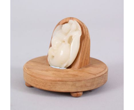 A GOOD CHINESE JADE PENDANT OF A BOY WITH FISH, probably 19th century , fitted to a later stand, the pendant 4.5cm x 3 cm