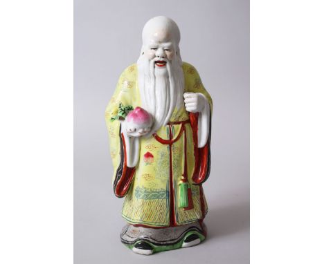 A GOOD CHINESE PORCELAIN MODEL OF GOD SHOU LOU, stood holding a fruit of some kind, wearing traditional imperial yellow colou