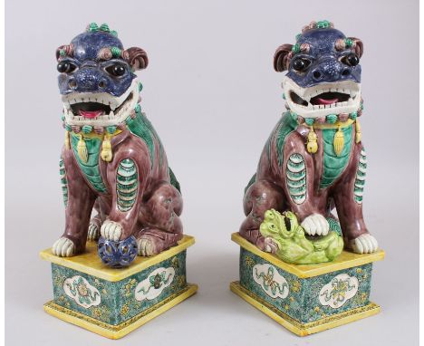 A PAIR OF 20TH CENTURY CHINESE PORCELAIN DOGS OF FOO / LION DOGS,  both posed upon pedestal bases with their paws upon a ball