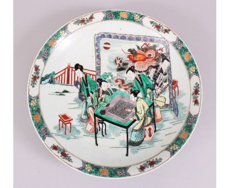 A CHINESE FAMILLE VERTE PORCELAIN DISH, decorated with scenes of five figures exterior playing a game, behind stands a large 