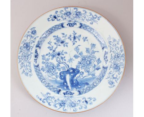 AN 18TH CENTURY CHINESE BLUE &amp; WHITE PLATE, decorated with formal scroll, flora and tree scenes, 28cm diameter.