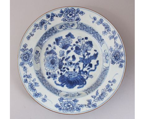 AN 18TH CENTURY CHINESE BLUE &amp; WHITE PLATE, decorated with formal scroll, flora and tree scenes, 23cm diameter.