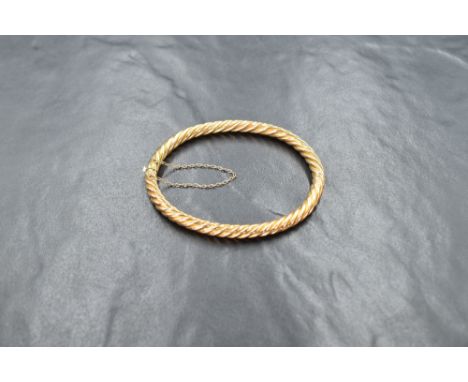 A high carat gold hinged bangle, of twisted design with safety chain, approx 8.9g
Condition report: Closed internal circumfer