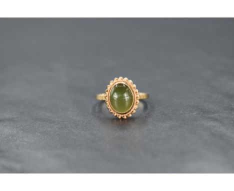 A 9ct gold green serpentine oval cabochon ring in a collared mount with twist wire decoration, size M &amp; approx 2.2g