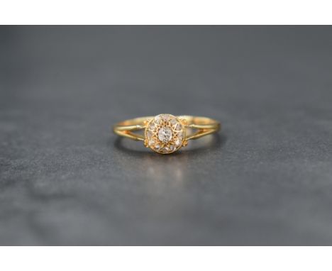 A 1920's 18ct gold diamond cushion cluster ring having a central diamond with surrounding old cut diamonds in a star burst st