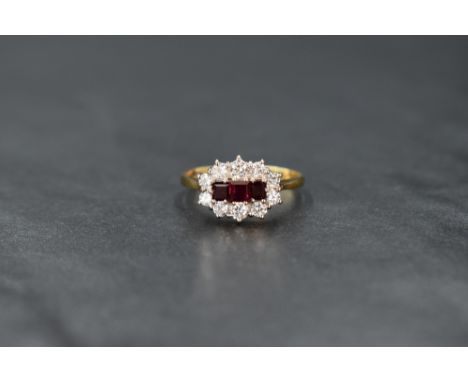 An 18ct gold ruby and diamond cluster ring having three baguette cut central rubies within an oval ten stone brilliant cut di