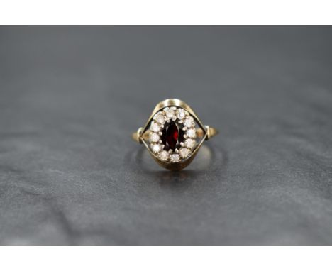 A garnet and clear paste cluster ring having a claw set mount with split shoulders on a 9ct rose gold loop, size Q &amp; appr