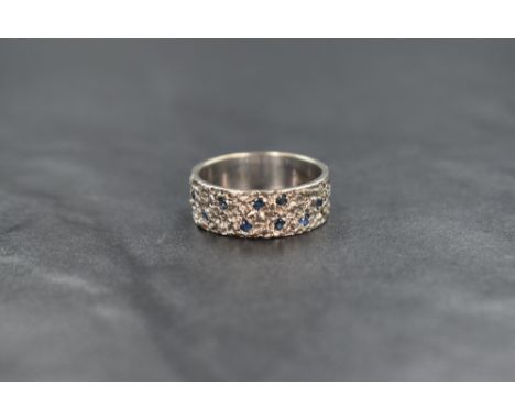 A 1960's 18ct white gold band ring having nine inset small sapphires and a bark effect finish, size O &amp; approx 6.1g