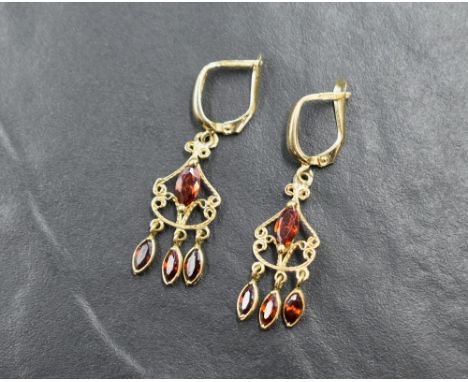 A pair of 9ct gold chandelier style earrings having clip loop fastenings and red/orange coloured stones in decorative drops, 