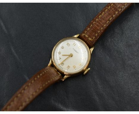 A lady's 9ct gold wrist watch by Tissot having Arabic numeral dial to champagne face in a plain gold case on a tan leather st