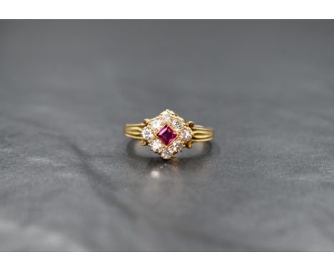 A yellow metal (presumed to be gold) ruby and diamond cluster ring, the central princess cut ruby with an eight old cut diamo