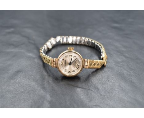 A lady's 19970's 9ct gold wrist watch by Excalibur having an Arabic numeral dial to circular face in a plain gold case on a g