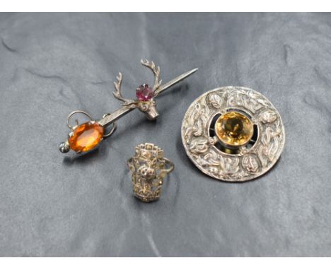 A silver citrine Celtic shield brooch, the central round cut citrine with a silver surround having embossed Celtic motif desi
