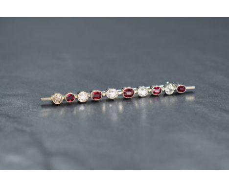 A white metal ruby and diamond bar brooch marked 18ct, the alternating mixed oval cut rubies and diamond in bezel settings, 4