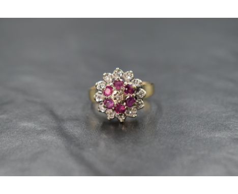 A 9ct gold ruby and diamond cluster ring, the central illusion set diamond chip with a six round cut ruby surround and a furt
