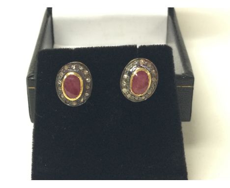 A pair of oval ruby and R/C diamond halo studs in gold plated silver. Ruby 0.28ct and 0.15ct diamonds approx. Postage B