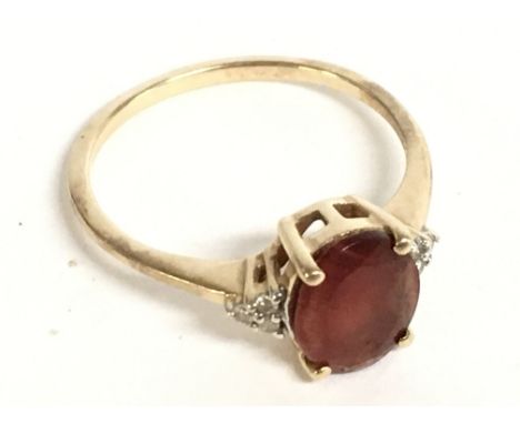 A 9 carat gold ring wet with an oval cornelian stone and small diamonds. Size S. 2.7g Postage category A