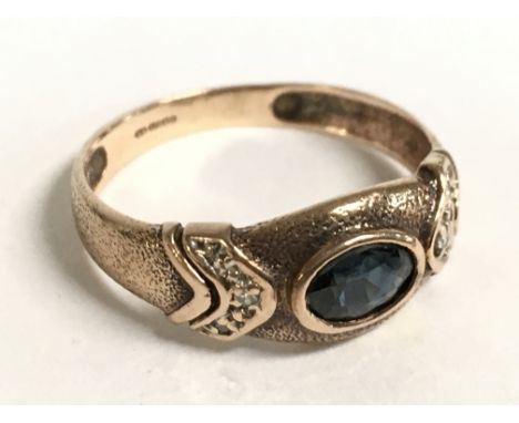 A 9 carat gold ring set with a sapphire stone and diamond shards. Size O. 2.1g Postage category A