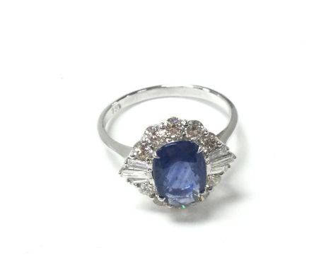An 18ct white gold ring set with oval-cut sapphire surrounded by RBC cut and baguette cut diamonds with certificate. Size O. 