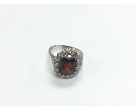 An 18ct gold ring set with a central garnet surrounded by diamonds, approx 6g and approx size N. Shipping category A.
