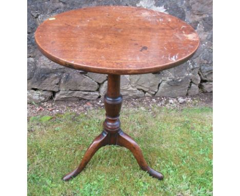 A 19th century oak tilt top tripod table, raised on a turned column, with three outswept supports, diameter 23ins, height 29i