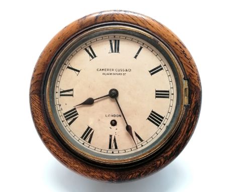 Antique oak cased wall clock retailed by Camerer Cuss &amp; Co. London. Has key but no pendulum. 26cm diameter. Painted dial 