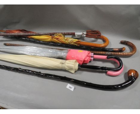 A selection of walking sticks and umbrellas to include a shooting stick 