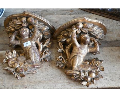 A pair of gilt over red lacquer shelf brackets carved with monkeys and peach trees, 36 cm high