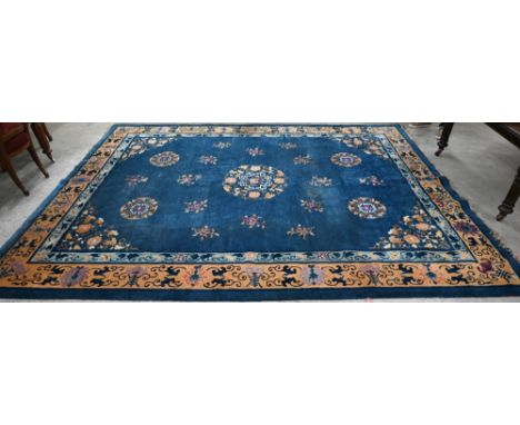 A Mid-Century Chinese Peking carpet, scattered design with floral sprays and roundels on blue ground, beige border with bats,