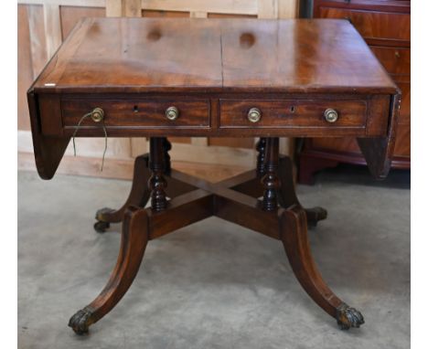 A Regency mahogany sofa table with two drawers and quadraform base with turned pillars and out-swept legs with brass paw caps