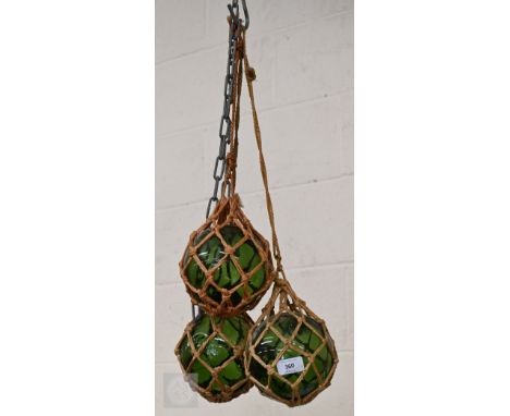 Three vintage green glass fishing net floats in rope nets 