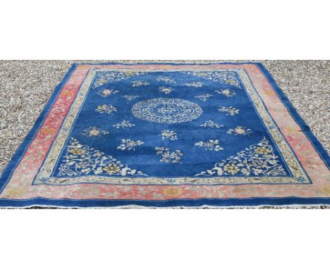 An antique blue ground Tibetan carpet, with floral design and beige and puce borders, worn